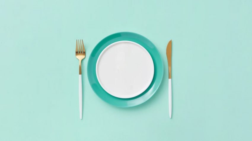 Teal plate set with fork and knife on a matching background. Minimalist and modern design.